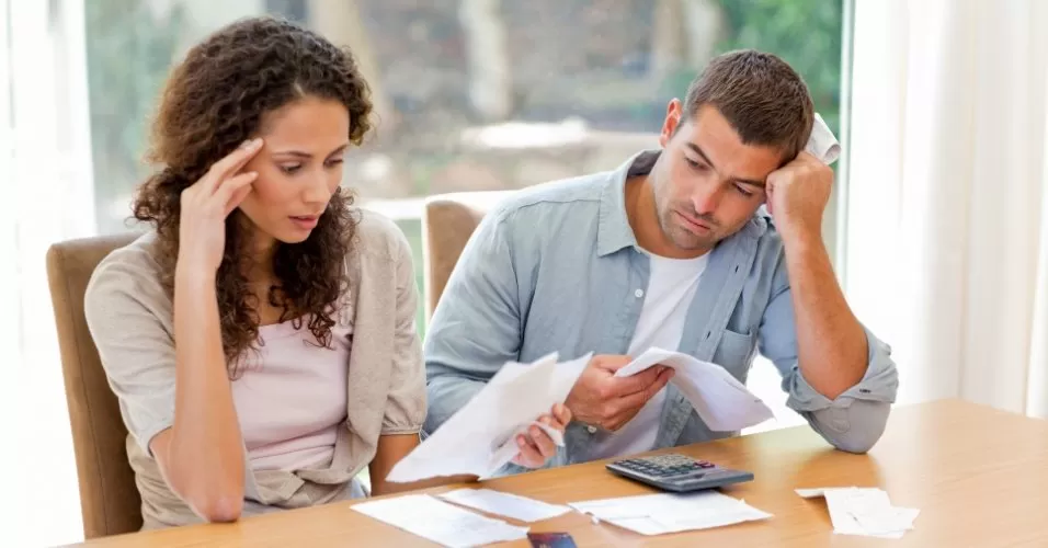 Casal preocupado analisando contas após dificuldade para financiar apartamento em Londrina